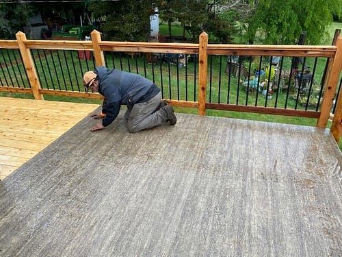 A man is kneeling down on a deck.