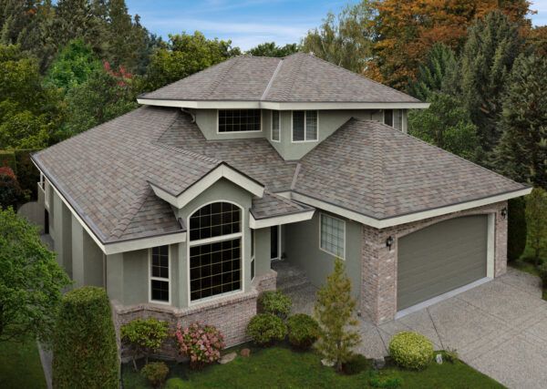 An aerial view of a large house with a gray roof surrounded by trees.