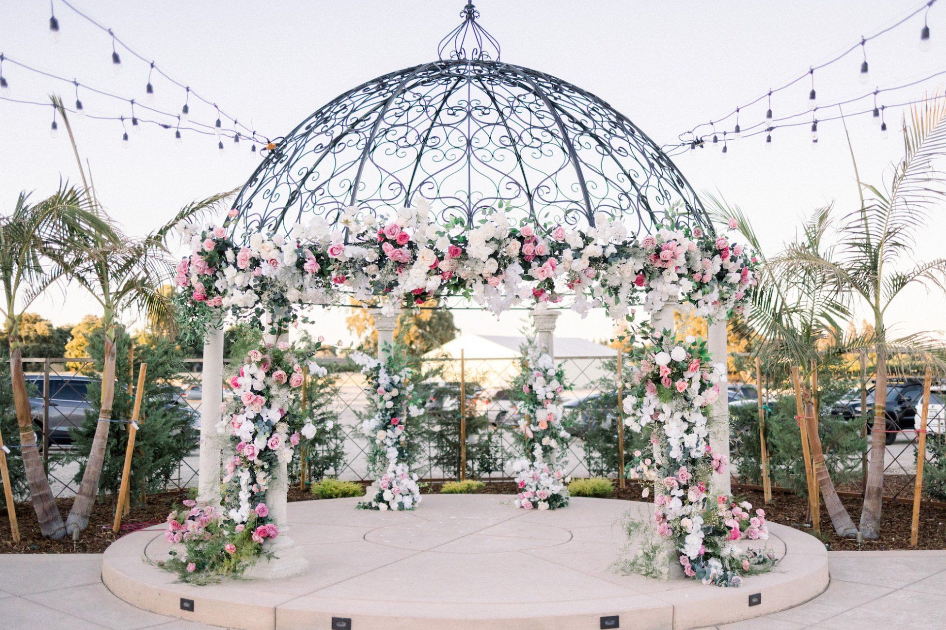 A gazebo decorated with pink and white flowers for a wedding ceremony.
