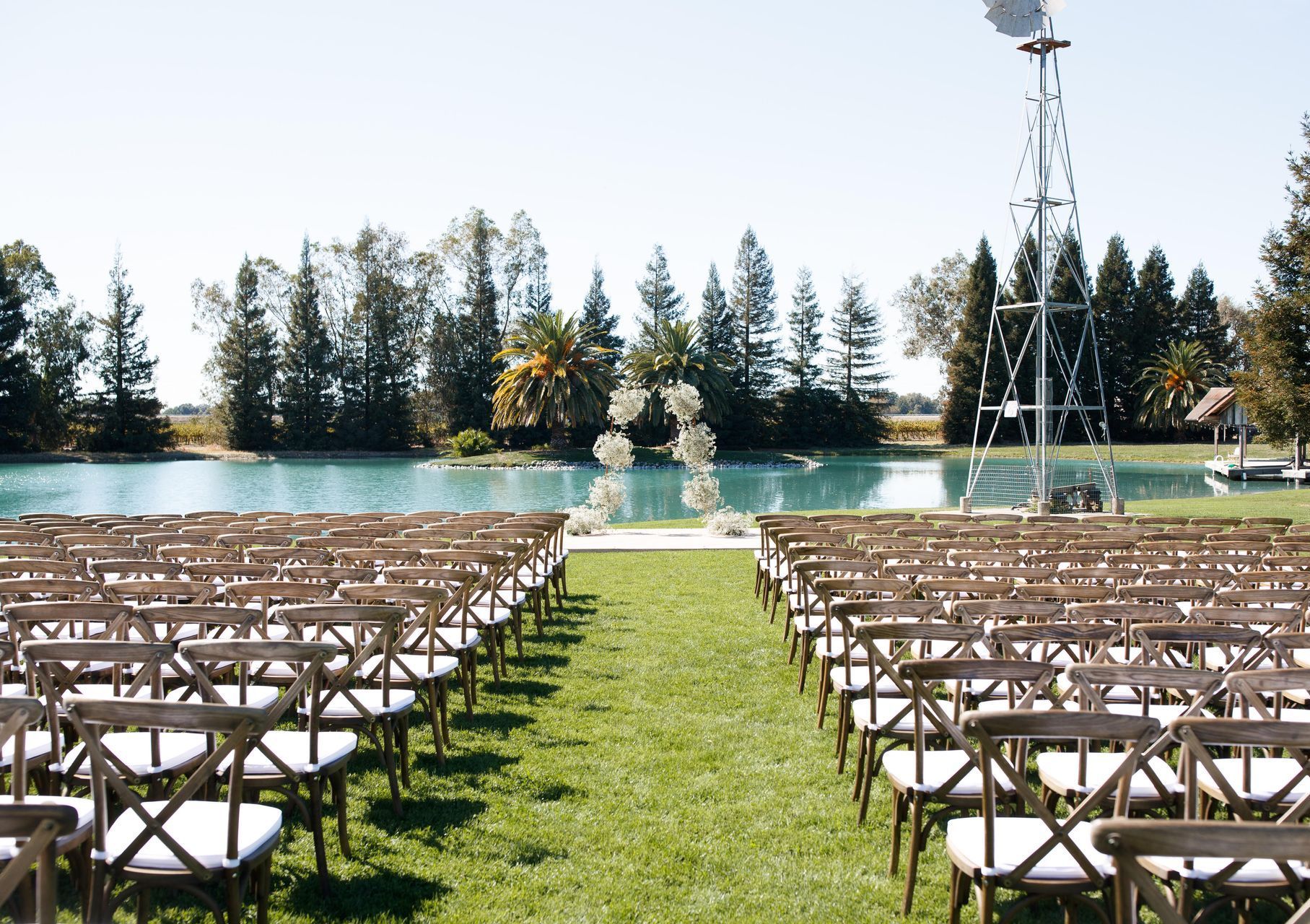 Rows of chairs are lined up in front of a lake for a wedding ceremony.