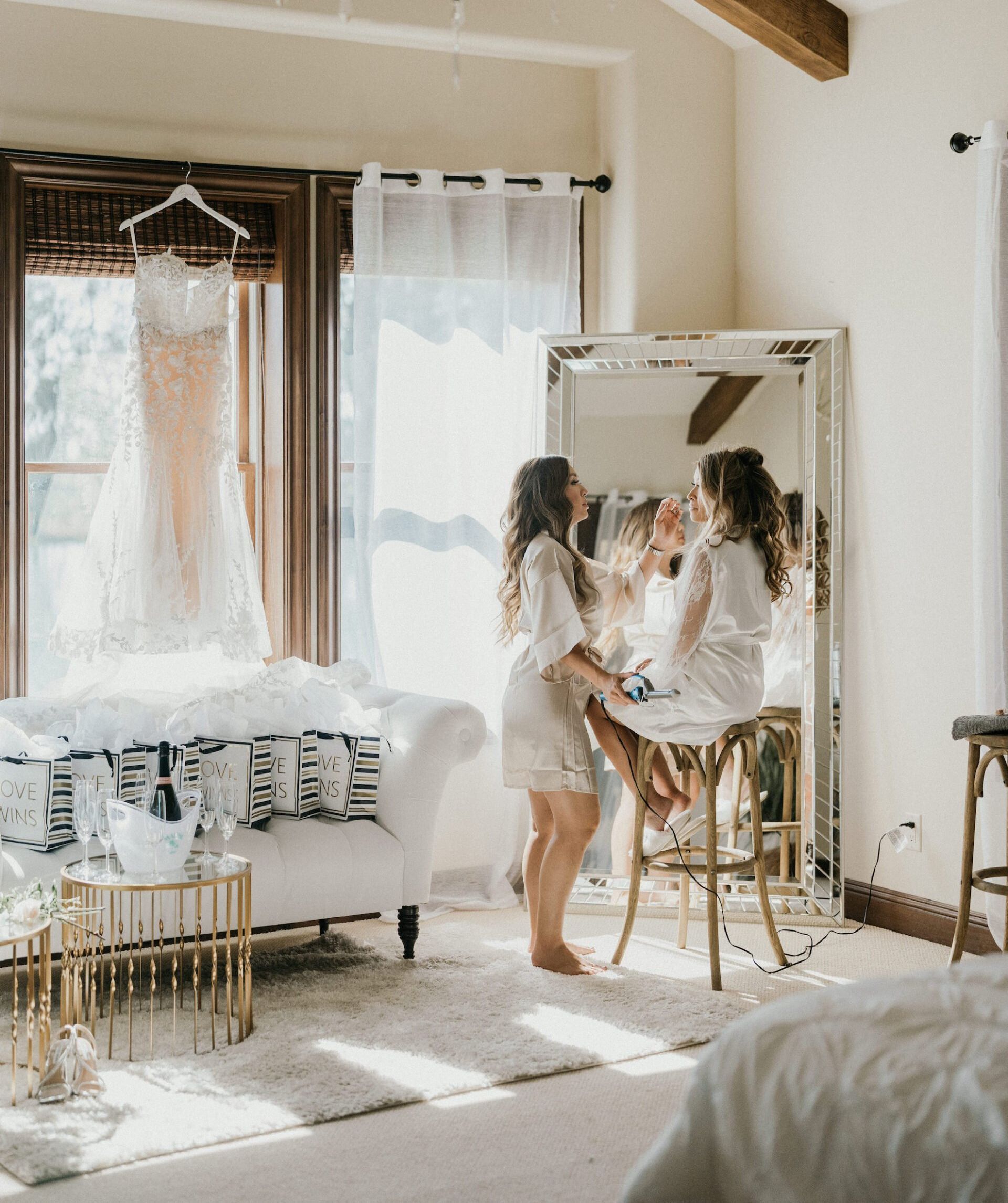 A woman is getting her makeup done in front of a mirror in a room.