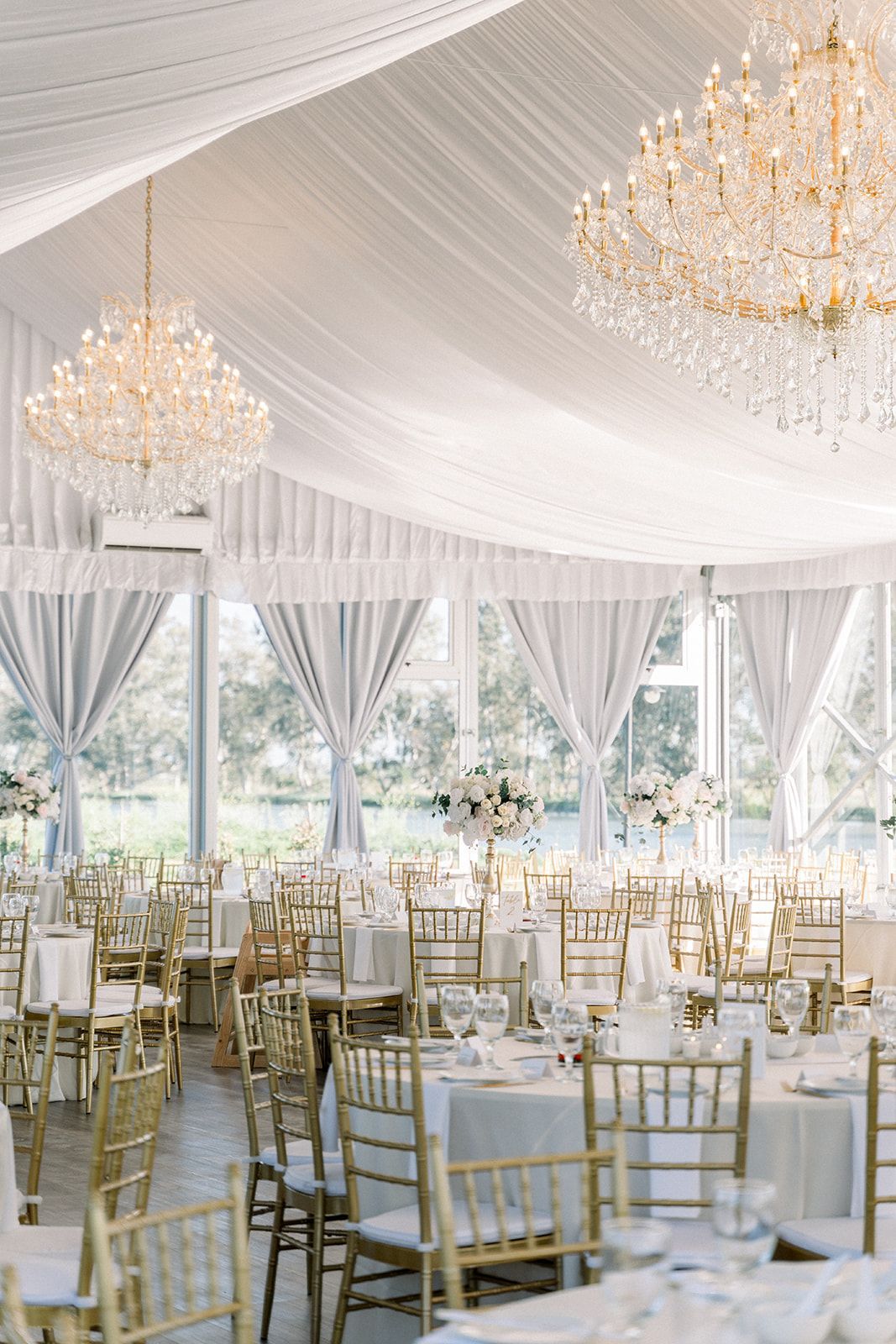 A large tent filled with tables and chairs and chandeliers.