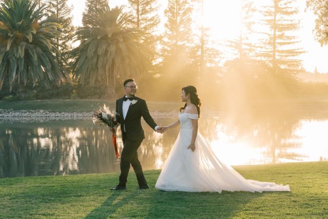 newly married bride and groom walking on lawn with a lake in the background