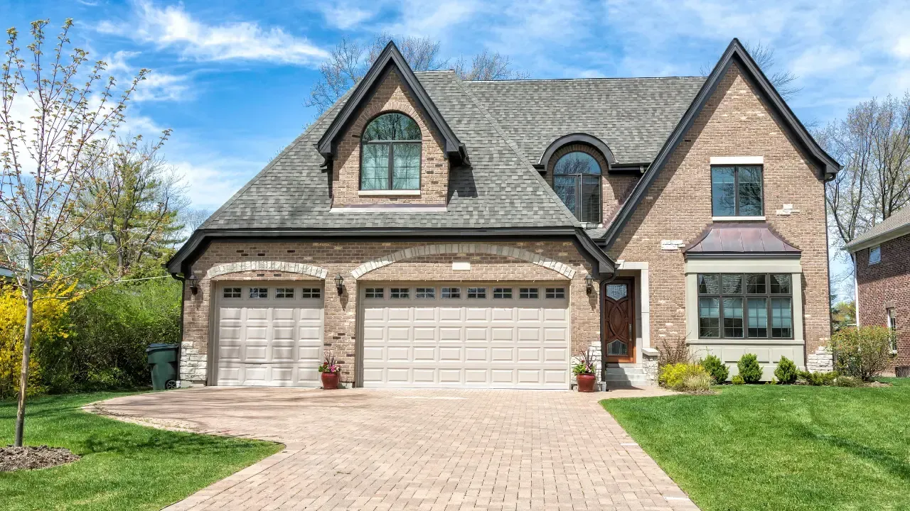 A large brick house with two garage doors and a brick driveway.