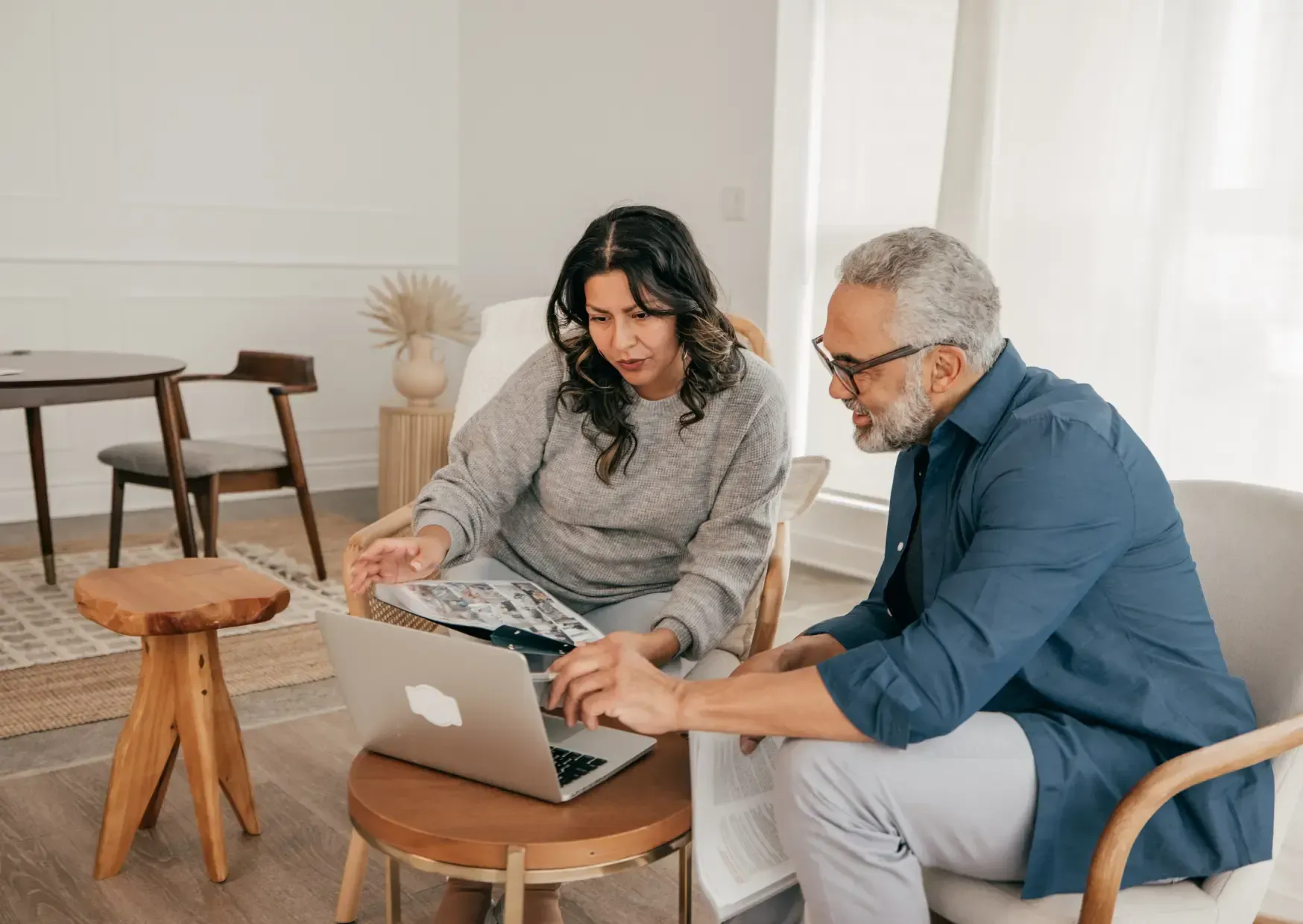 Two people collaborating on a laptop in a bright living room