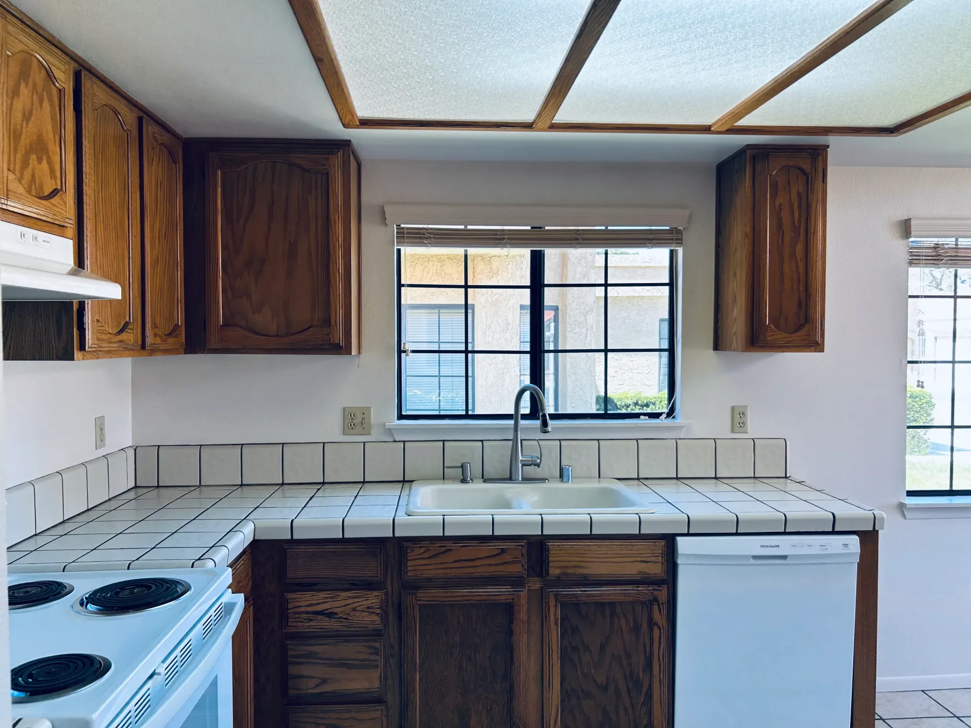 A kitchen with a sink , stove , dishwasher and window.