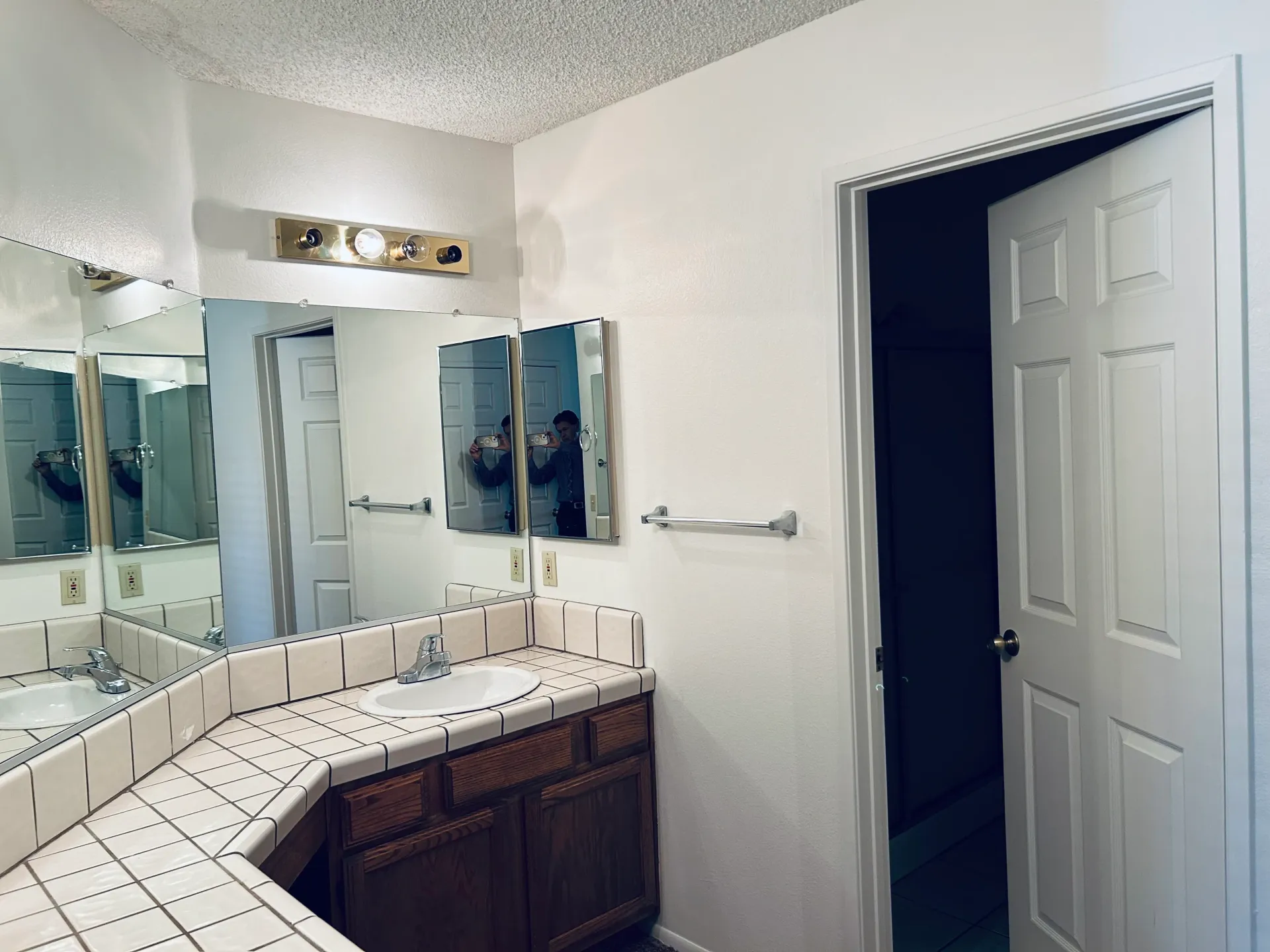 A bathroom with a sink , mirrors and a door