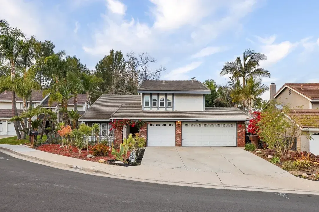 A large house with three garage doors is sitting on top of a hill.