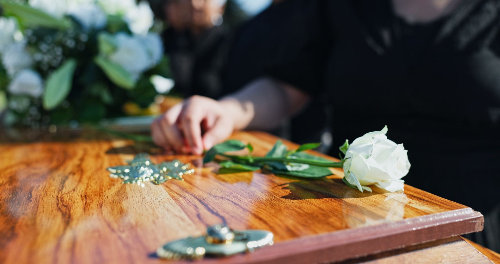 A man in a suit is sitting at a coffin at a funeral.