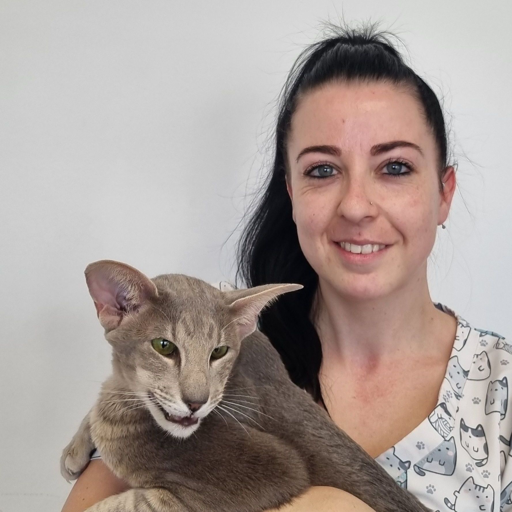 Une femme tient un chat dans ses bras et sourit