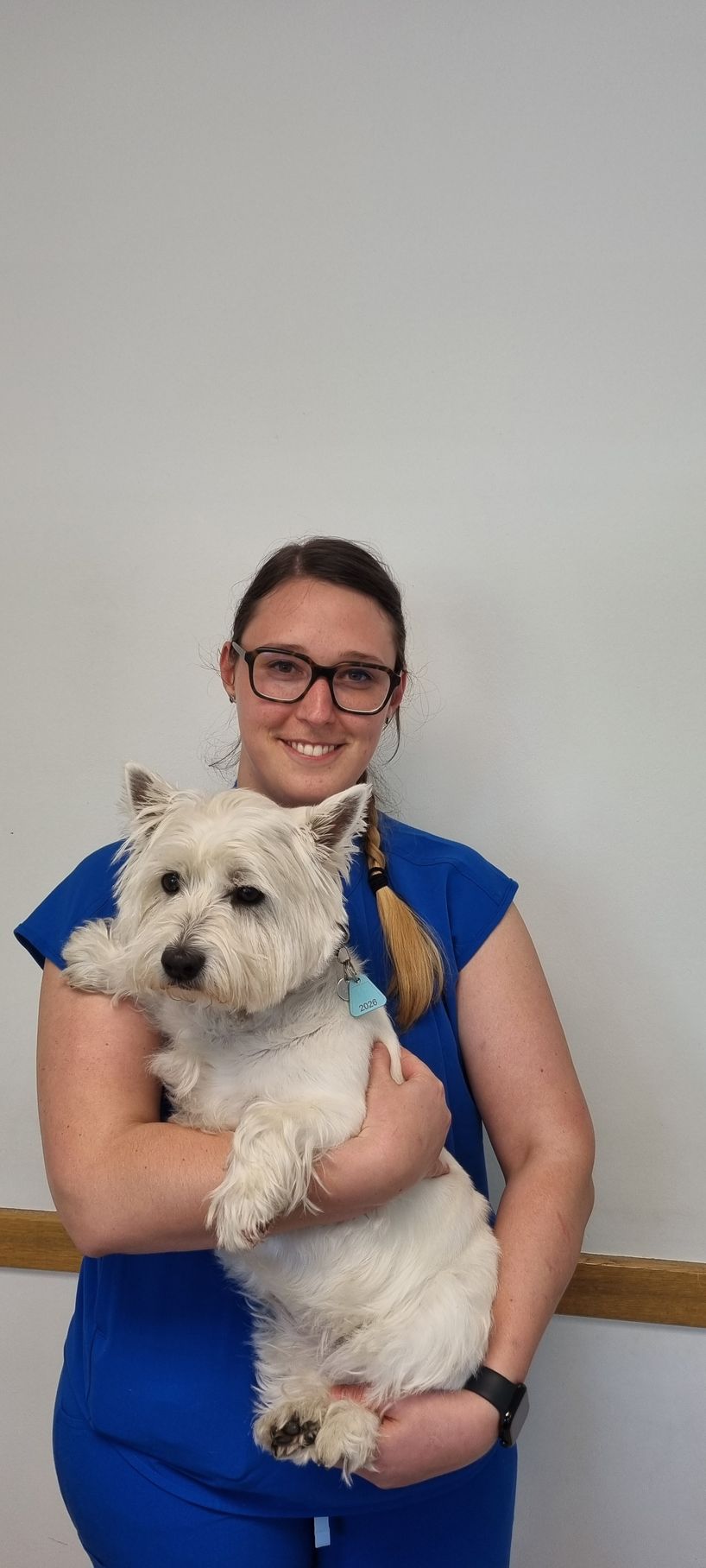 Une femme dans un maquis vert tient un chien noir et marron.