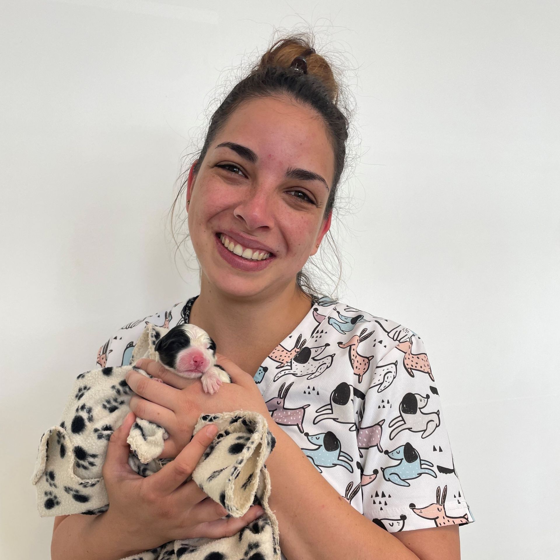 Une femme tient un chiot dans ses bras et sourit.