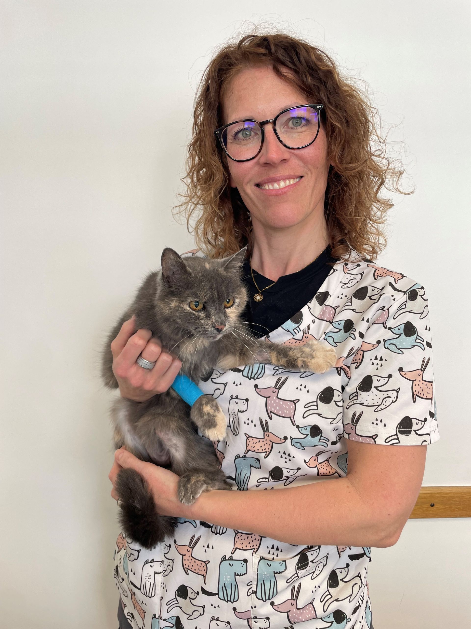 Une femme portant des lunettes tient un chat dans ses bras.
