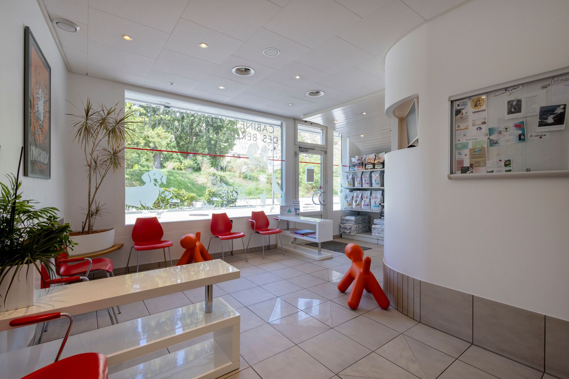 Une salle d'attente avec des chaises rouges, une table et une fenêtre.