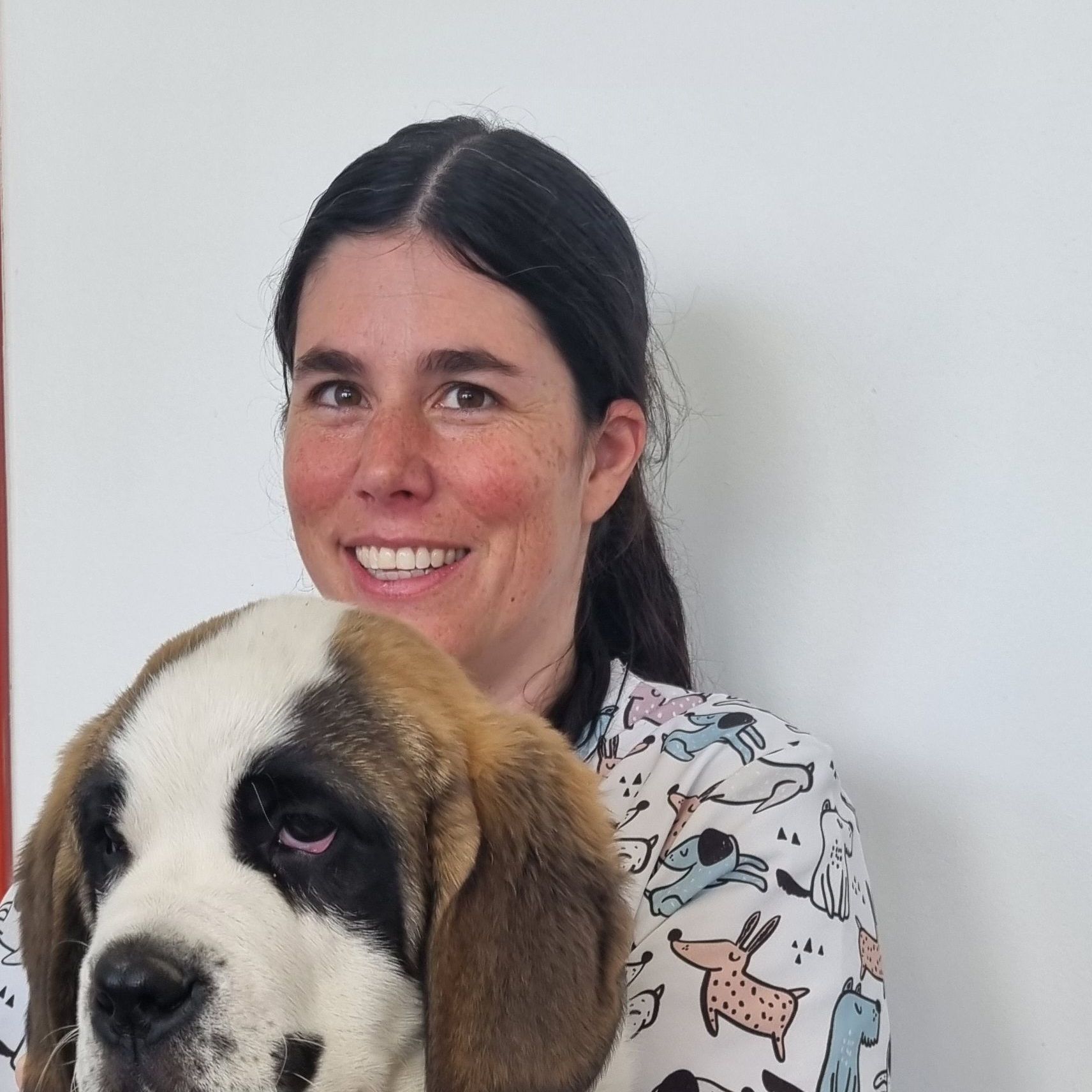 Une femme tient un chien marron et blanc et sourit