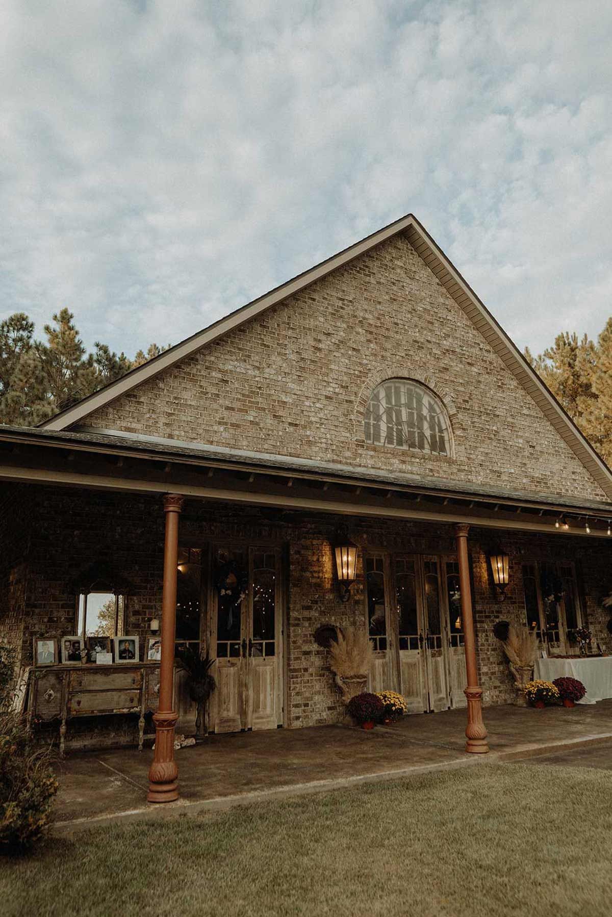 Stone barn with covered porch, adorned with decorations, under a cloudy sky.