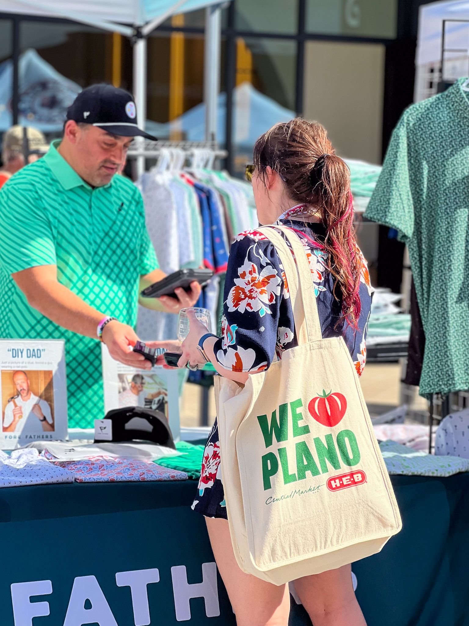 Attendee holding a Visit Plano HEB bag while visiting a small business vendor booth.
