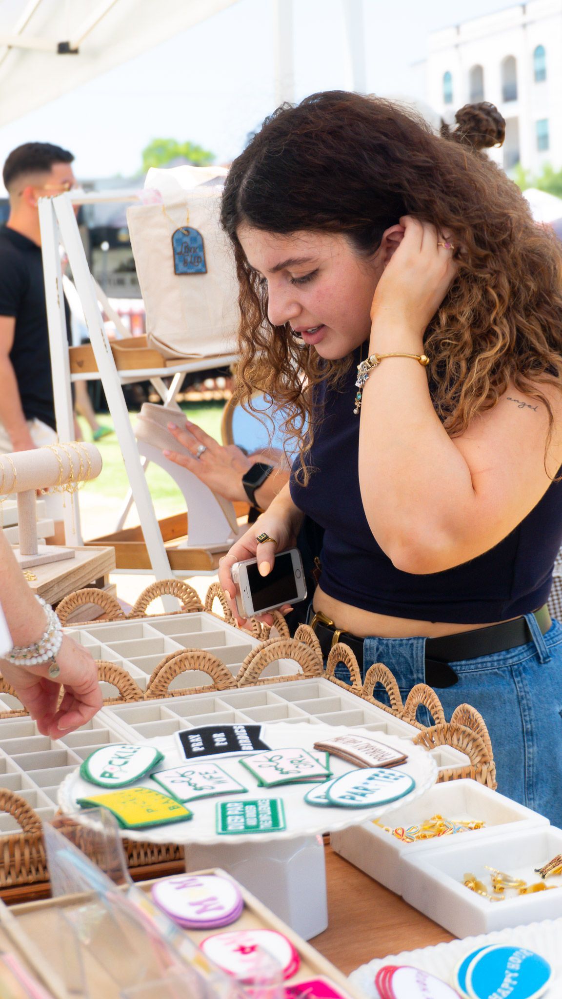 An customer browsing custom charms and jewelry at a local market pop up in DFW.