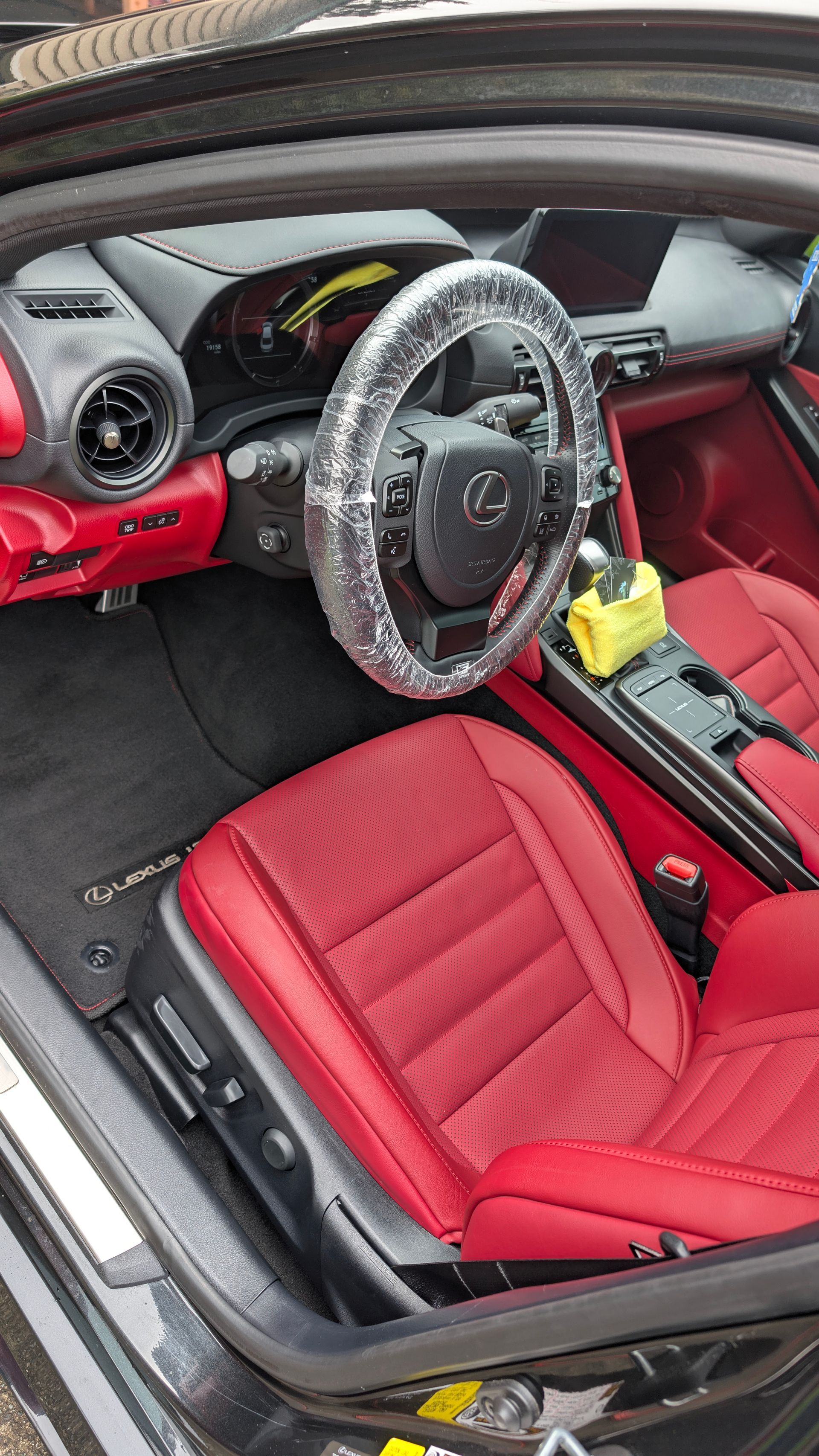 Red car interior with red seats, black steering wheel, and a yellow item hanging from the center console.
