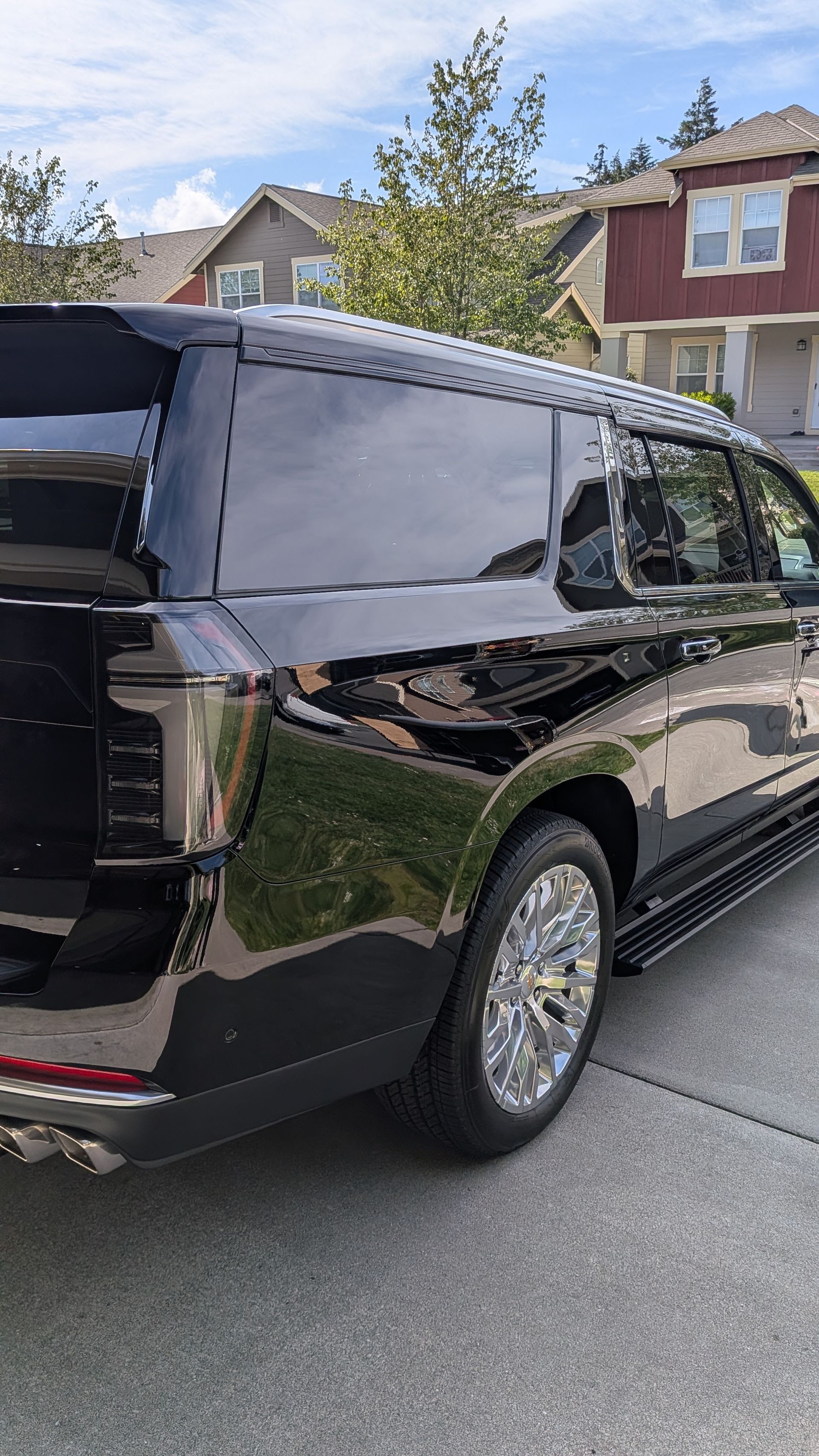 Black SUV parked on a suburban street with houses and trees in the background.