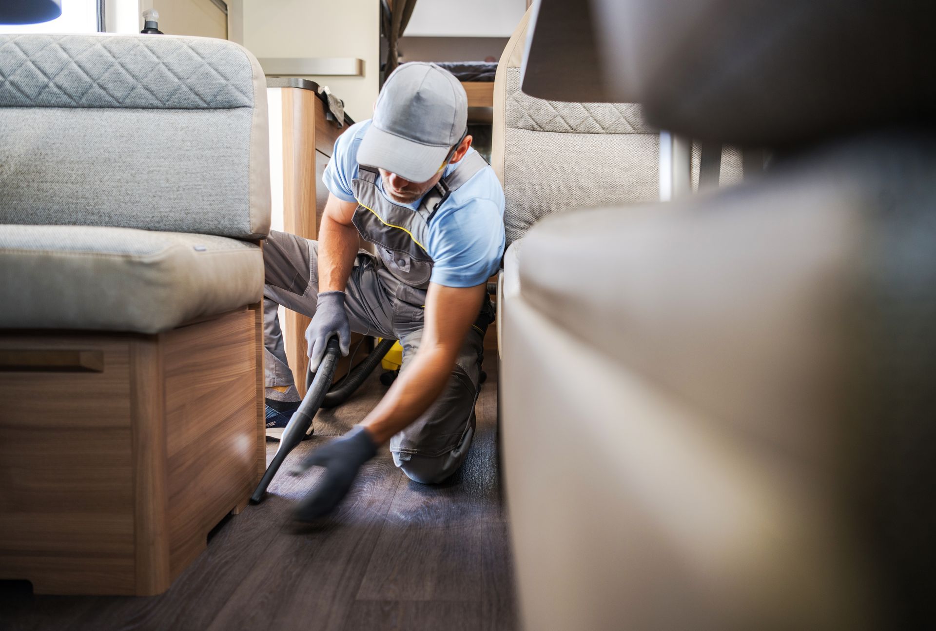Person vacuuming a carpeted living room between two sofas