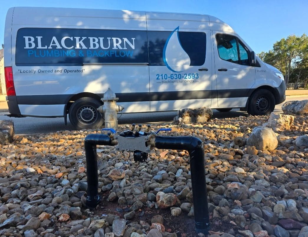 White Blackburn van parked on a rocky shoreline beside water, with a logo and blue graphics on the side
