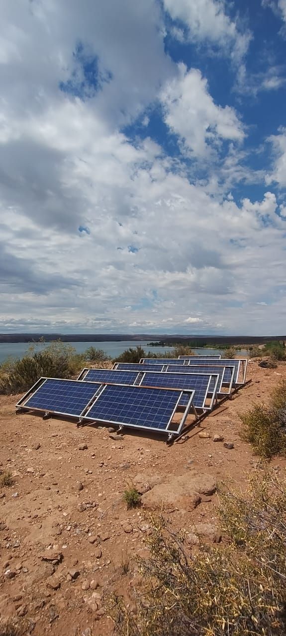 Paneles solares en un campo seco bajo un cielo azul nublado.