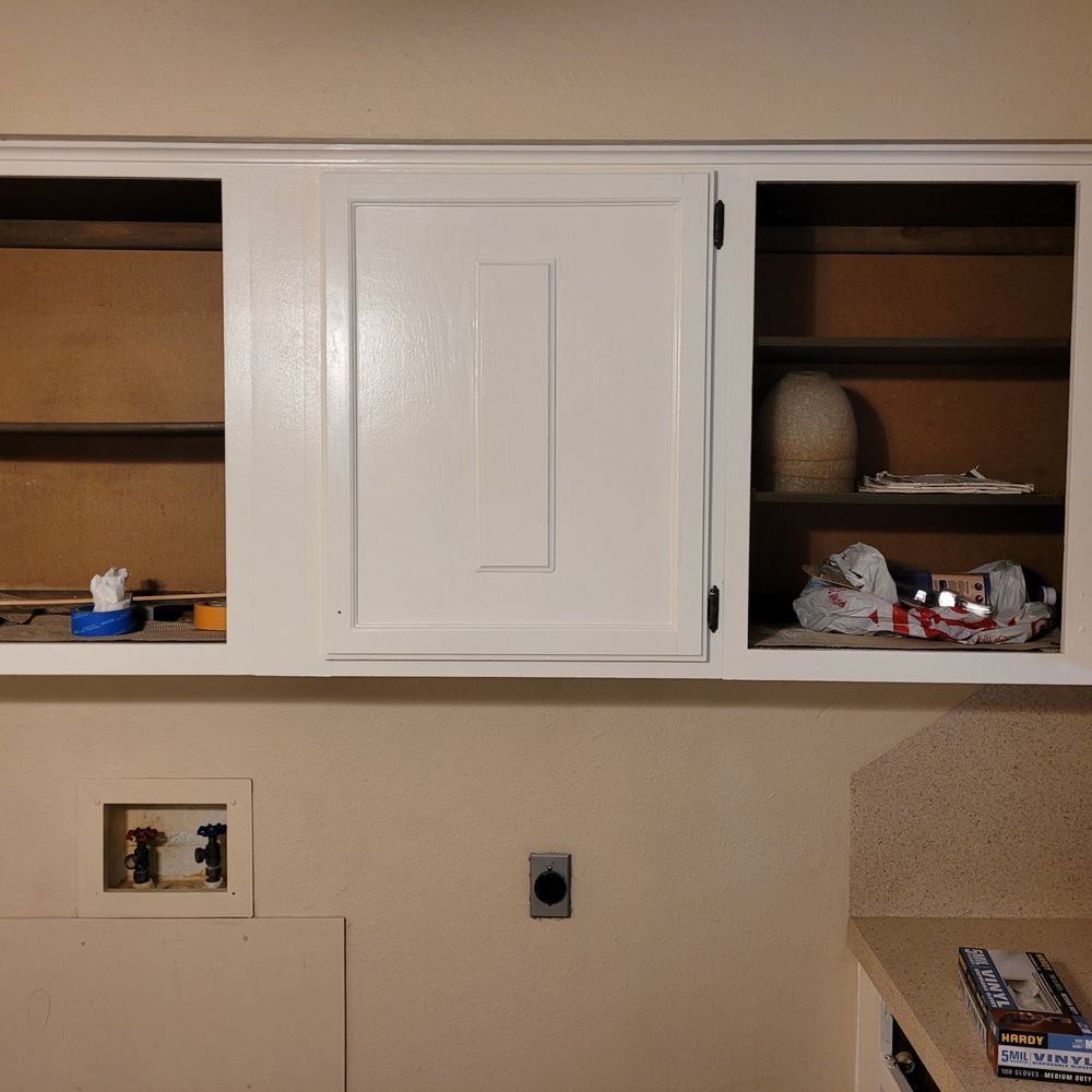 Kitchen wall cabinets with open shelves and items inside, plus beige walls and countertop below