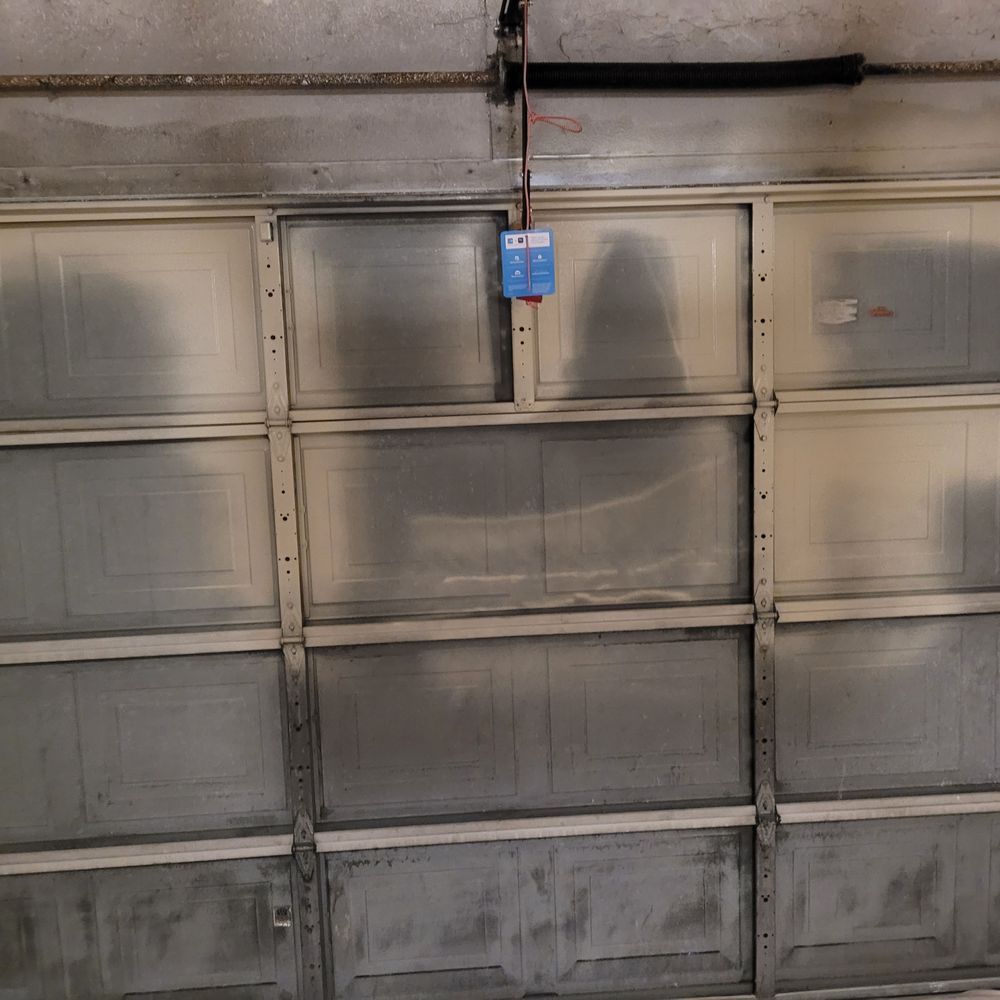 Closed garage door with a blue keypad opener hanging above it.
