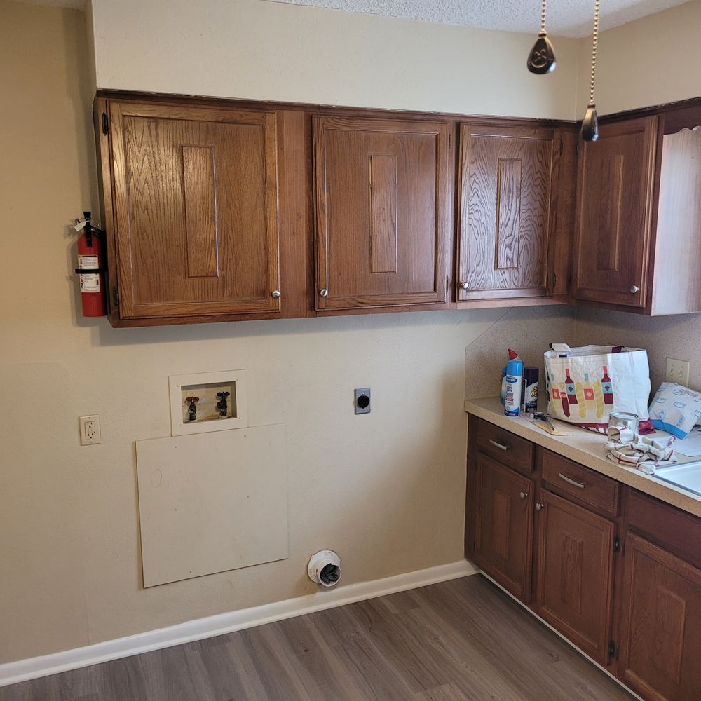 Empty kitchen with wood cabinets, countertop clutter, and a wall cutout for appliances.