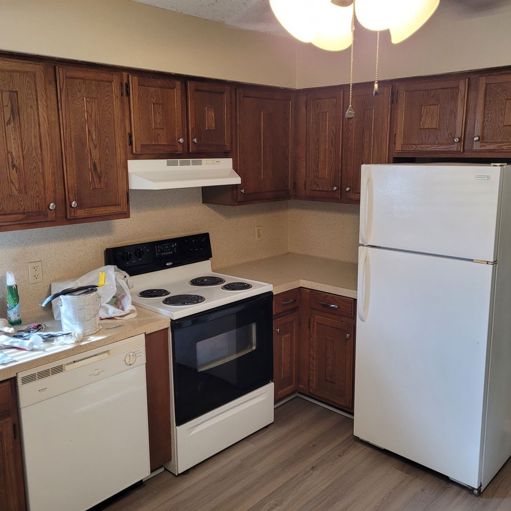 Small kitchen with dark wood cabinets, white appliances, and a refrigerator on the right.