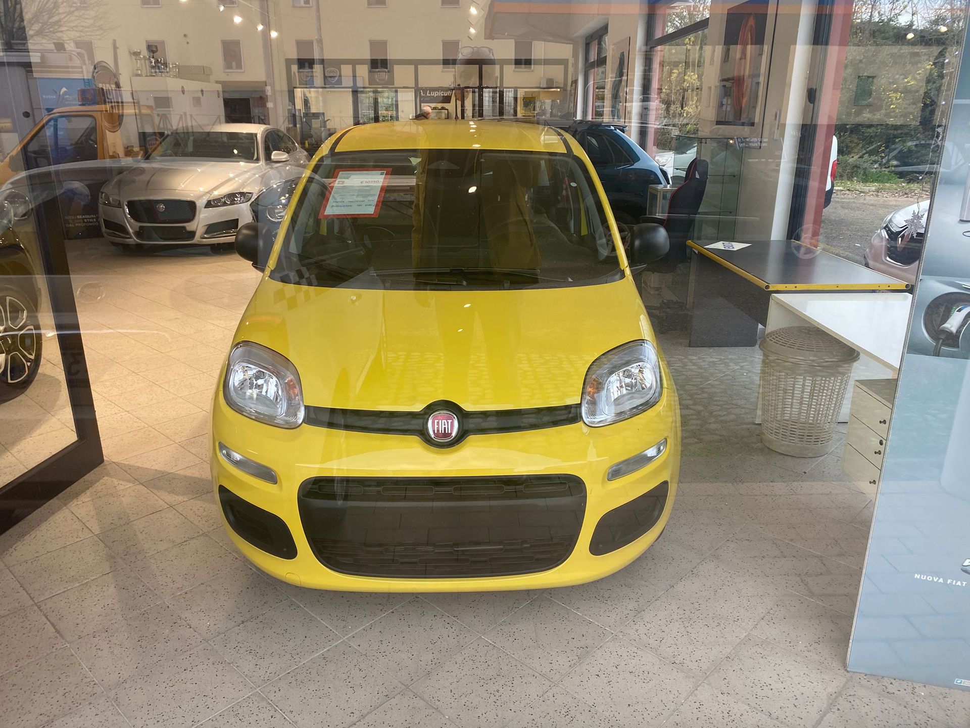Fiat hatchback gialla esposta all'interno di uno showroom, vista frontalmente.