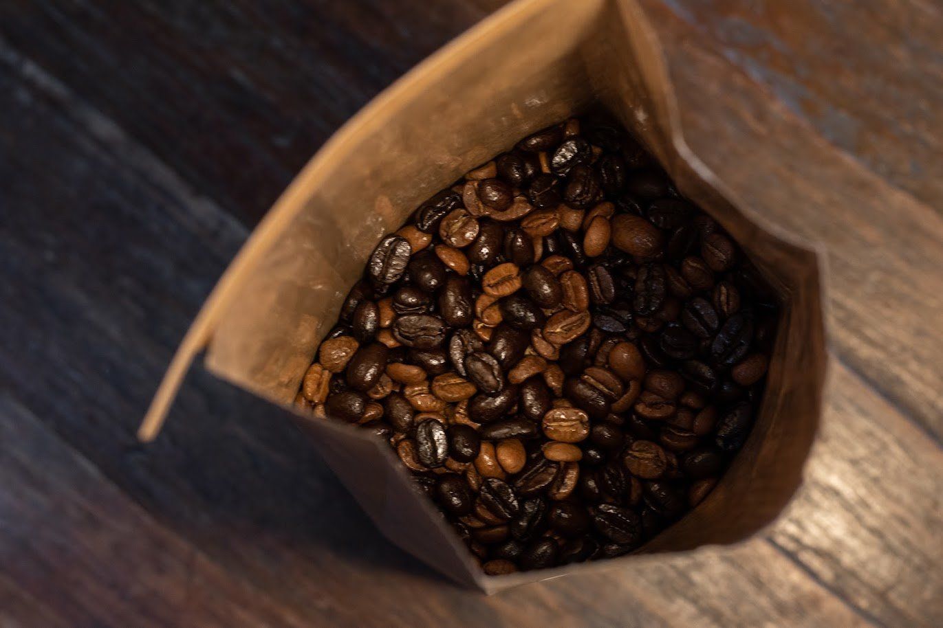 A bag full of coffee beans sitting on top of a wooden table