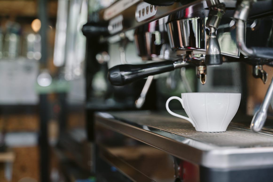A White Coffee Cup Sits on the Metal Drip Tray — Premiair Refrigeration, Air Conditioning & Electrical in Tamworth, NSW