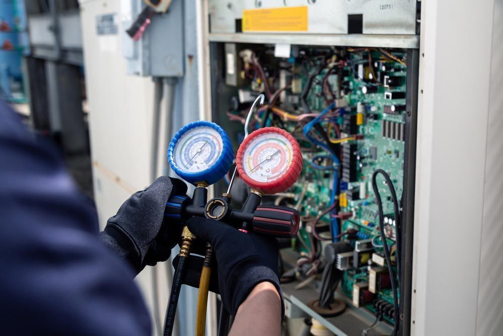 A Technician Holding a Manifold Gauge — Premiair Refrigeration, Air Conditioning & Electrical in Tamworth, NSW