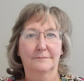Close-up portrait of a person wearing glasses, facing forward against a plain light background