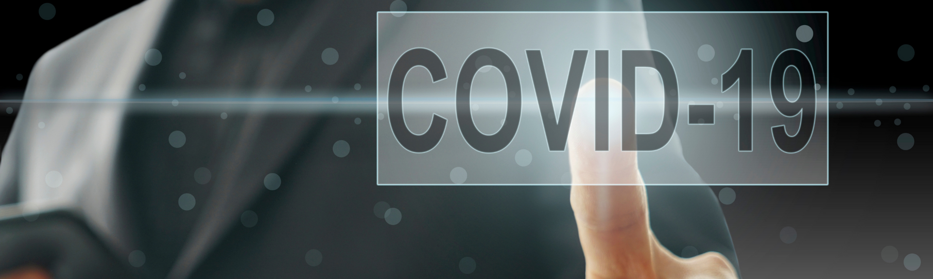Finger pointing at a transparent “COVID-19” label on a dark background.