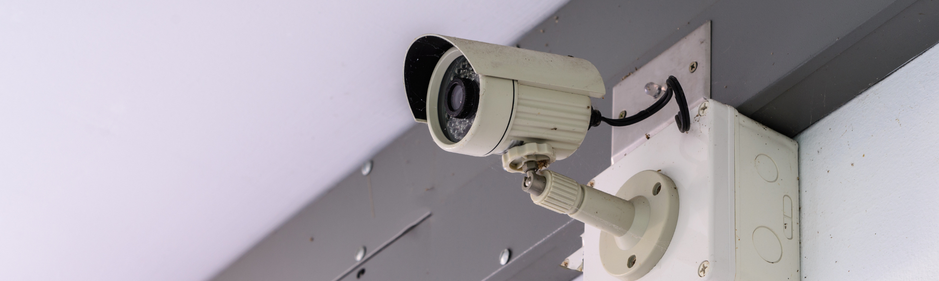 Security camera mounted on a wall, angled downward near a ceiling corner.
