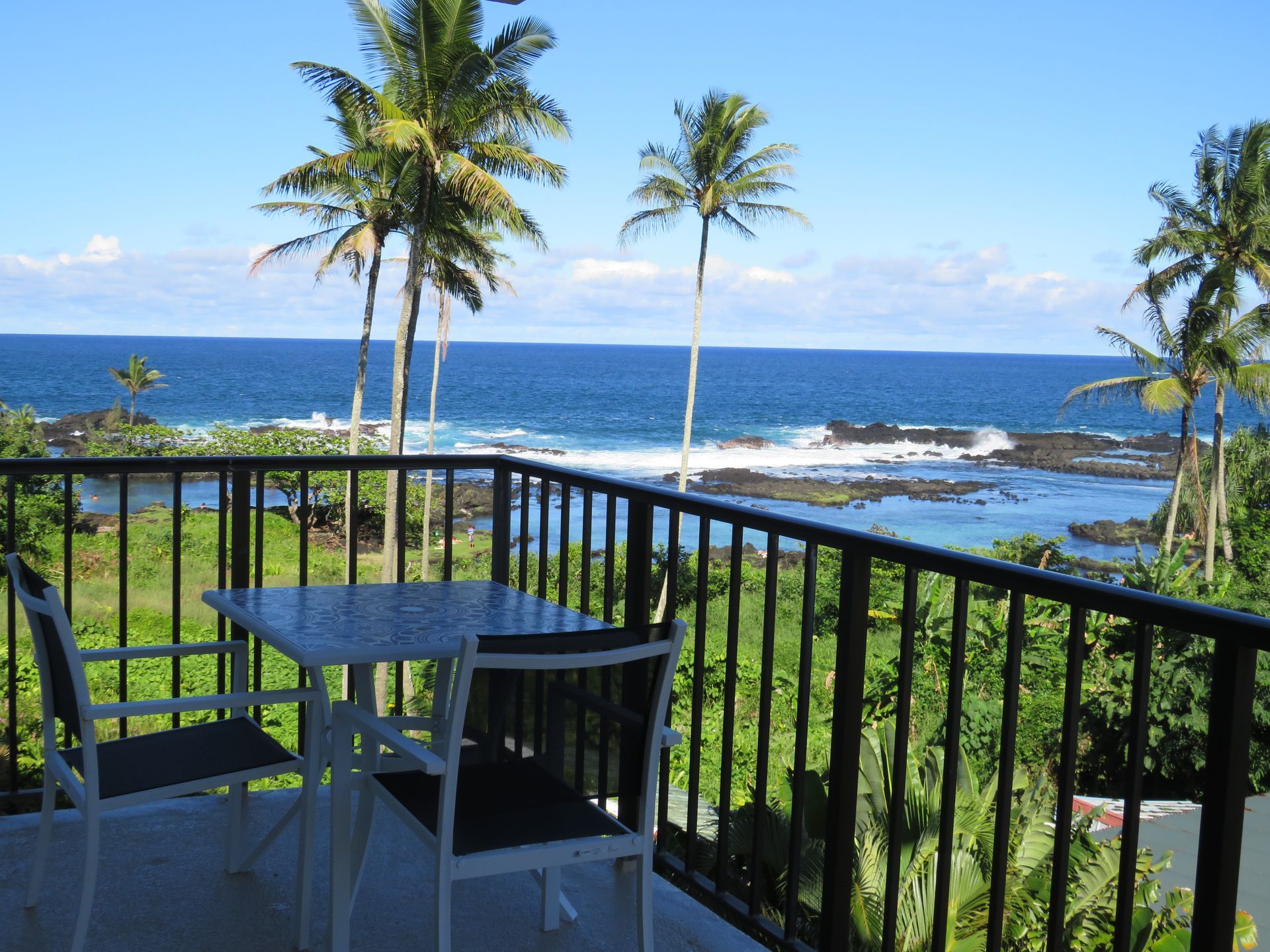 A balcony with a table and chairs overlooking the ocean