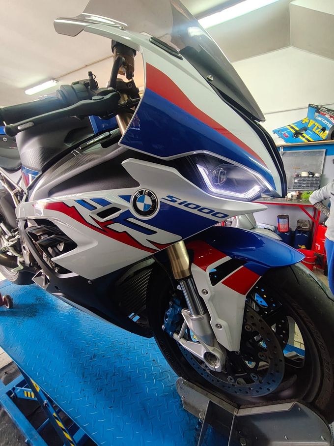 Scooter BMW bianco con grafiche da corsa rosse e blu su un piedistallo da esposizione in showroom.
