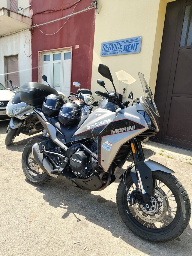 Due motociclette sportive nere e grigie parcheggiate davanti a un edificio rosso.