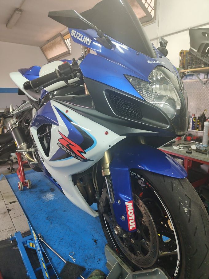 Motocicletta sportiva blu e bianca su un sollevatore da officina in un garage, vista frontale