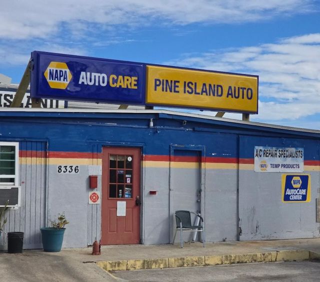 Pine Island Auto shop storefront with NAPA Auto Care sign, blue and yellow facade, and red door | Pine Island Auto