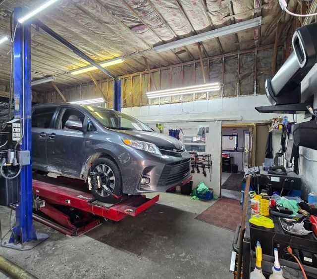 Gray SUV on a red lift in an auto repair shop, with tools and equipment around it | Pine Island Auto