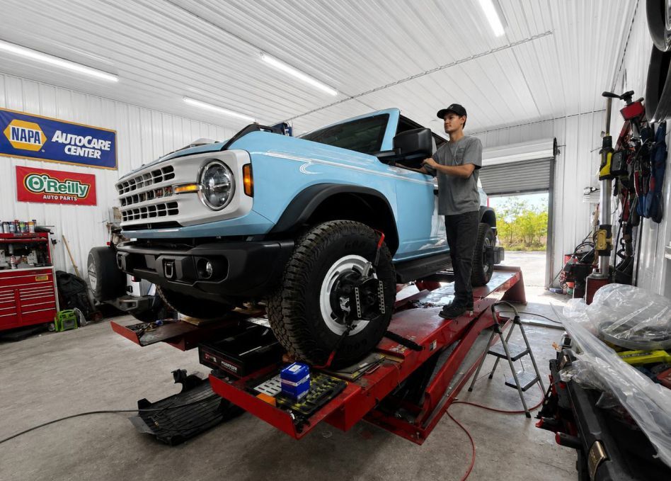 Black classic car in a garage with a silver car and mechanic equipment nearby | Pine Island Auto
