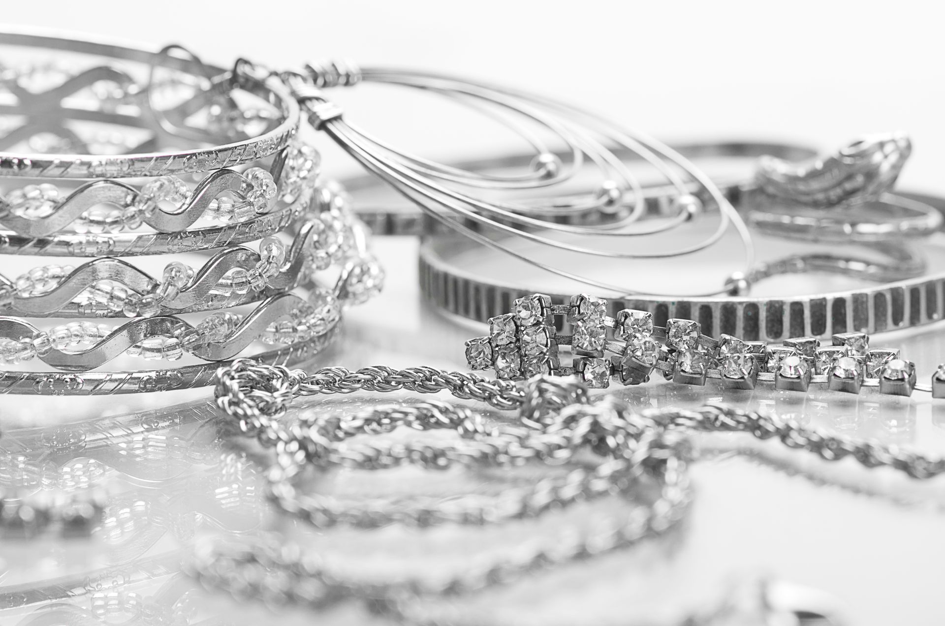 A collection of silver jewelry, including rings, chains, and decorative pieces, is displayed.