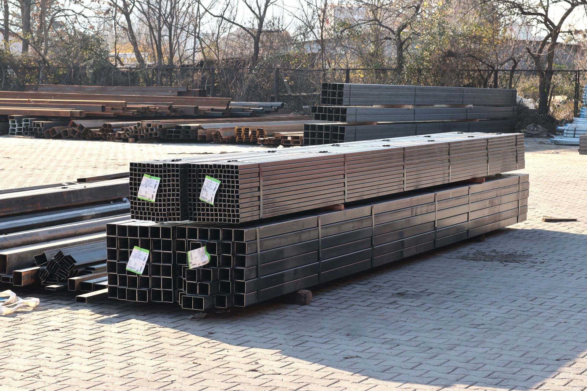 Stack of steel rectangular hollow sections placed on dirt ground at an outdoor construction site