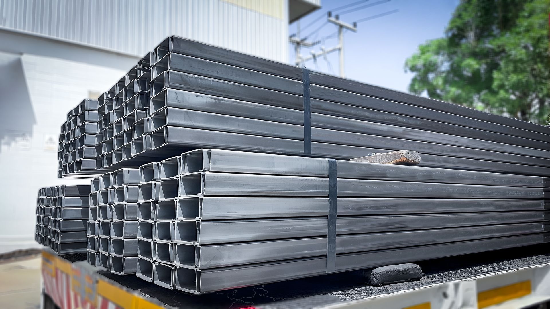 Large bunches of steel H-beams on top of a truck bed parked outdoors. Large bunches of steel H-beams on top of a truck bed parked outdoors.