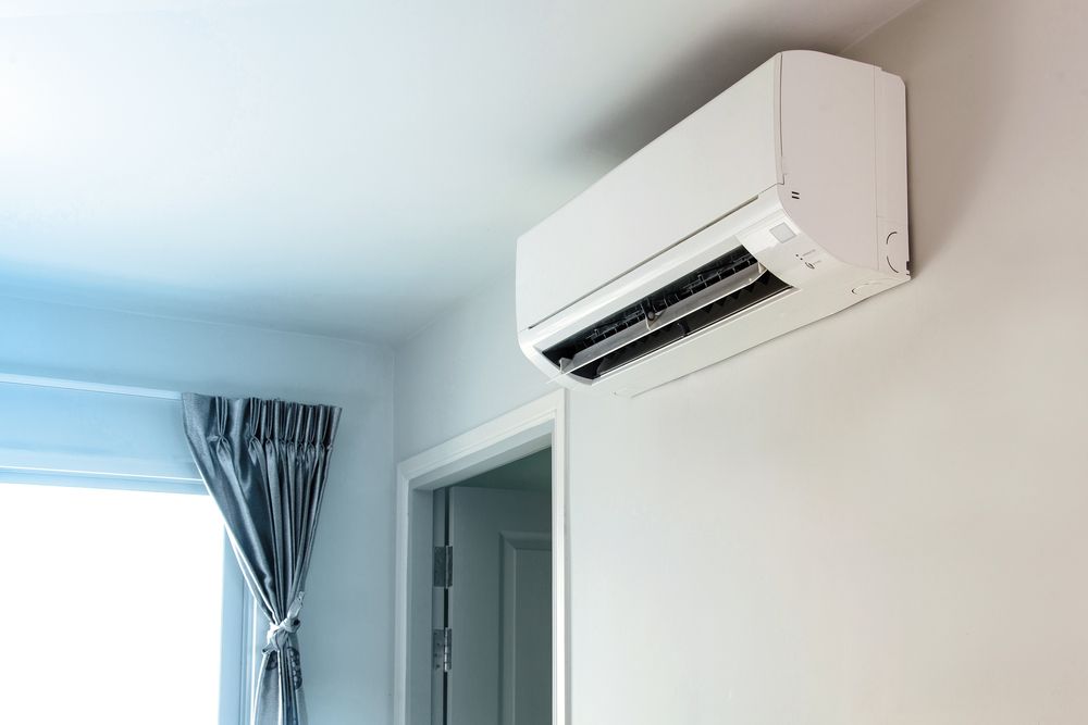 A White Air Conditioner is Hanging on a White Wall in a Room — Enterprise Air That's Cool in Burnett Heads, QLD