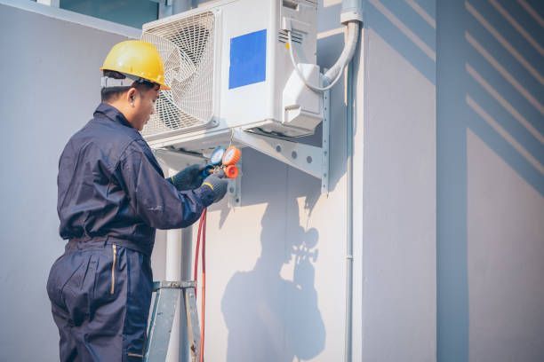 A Man is Working on an Air Conditioner on the Side of a Building — Enterprise Air That's Cool in South Kolan, QLD